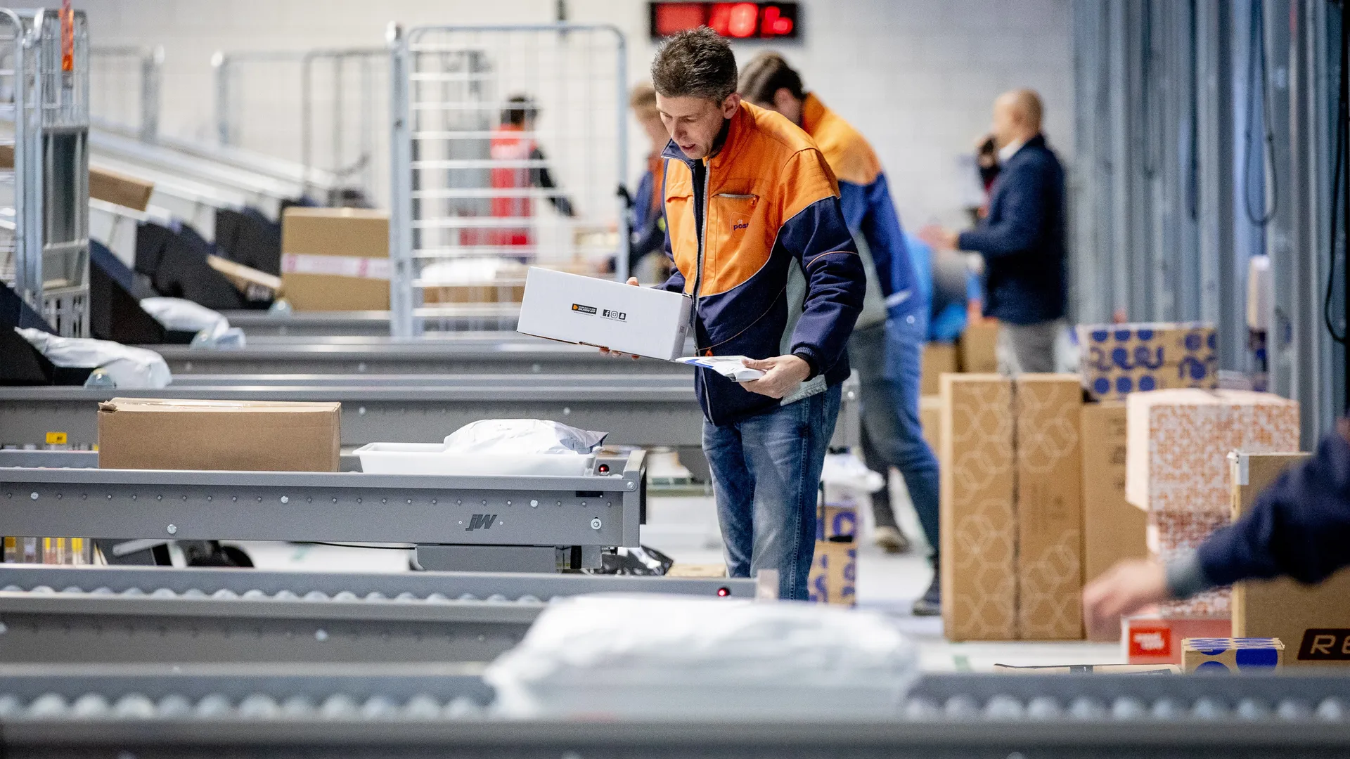 Medewerkers sorteren pakketten in het nieuwe pakketsorteercentrum van PostNL.