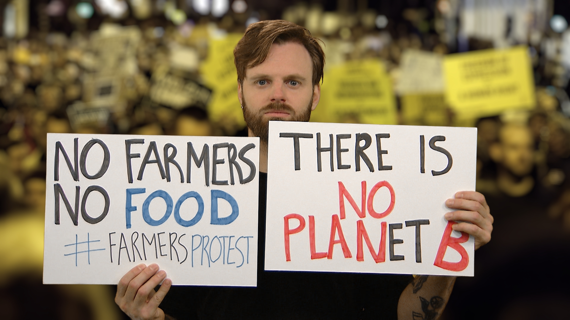 Tim Hofman houdt twee protestborden omhoog. Een met de tekst: 'No Farmers, No Food. #Famersprotest'. En een andere met de tekst: 'There is on Planet B'