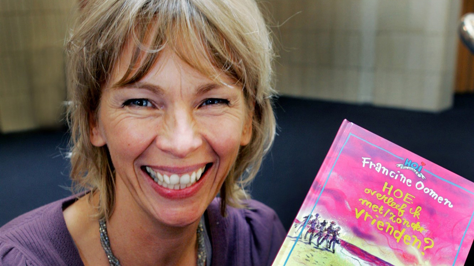 Francine Oomen met in haar handen haar boek 'Hoe overleef ik met/zonder vrienden'