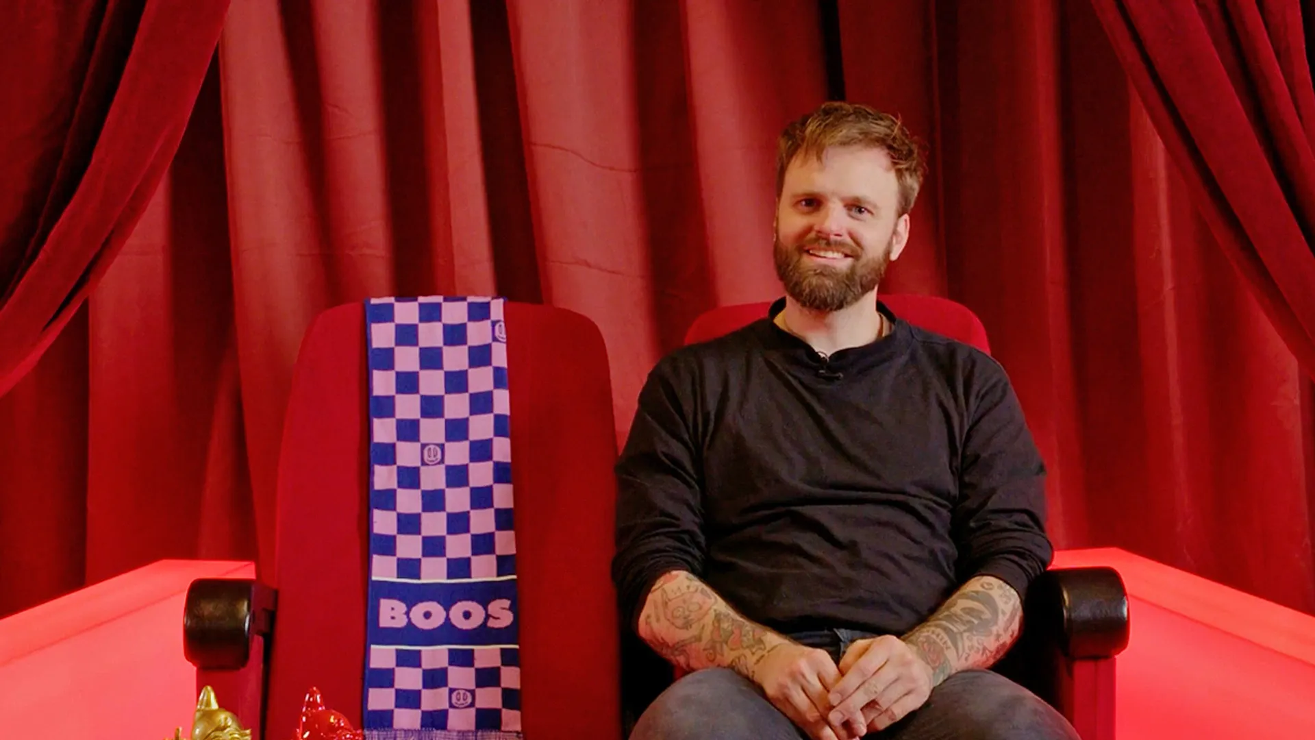 Tim Hofman met een sjaal van BOOS in een rode stoel